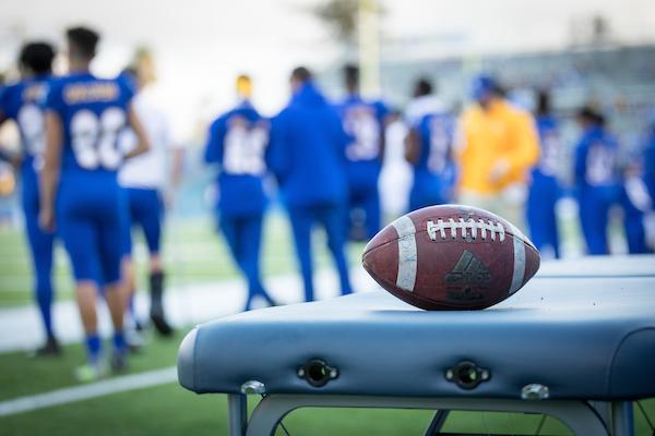 Football in focus on a bench with players in the background